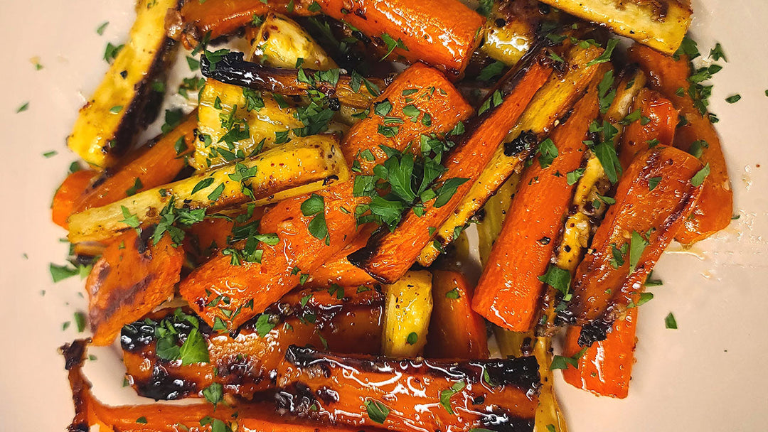 This image shows maple glazed carrots plated and garnished with fresh parsley.