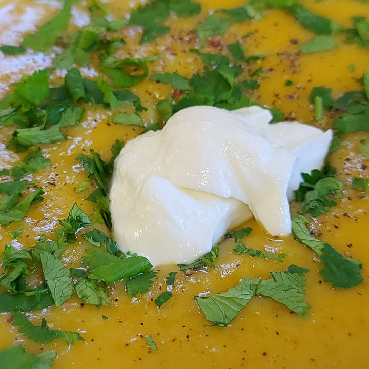 Greek yogurt and cilantro top a bowl of butternut squash soup.