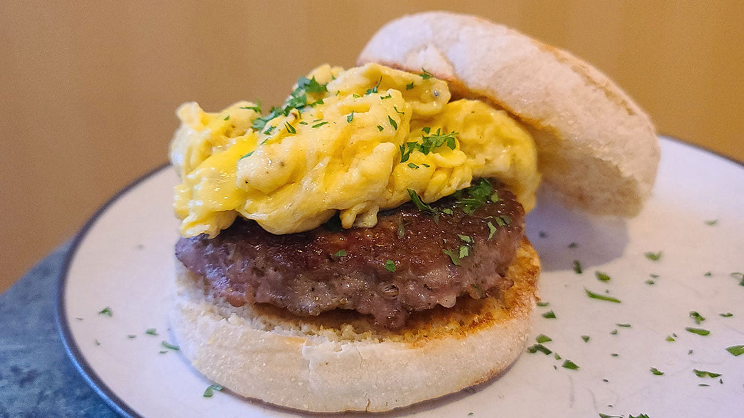 A maple sausage patty on an English Muffin with scrambled eggs on top.