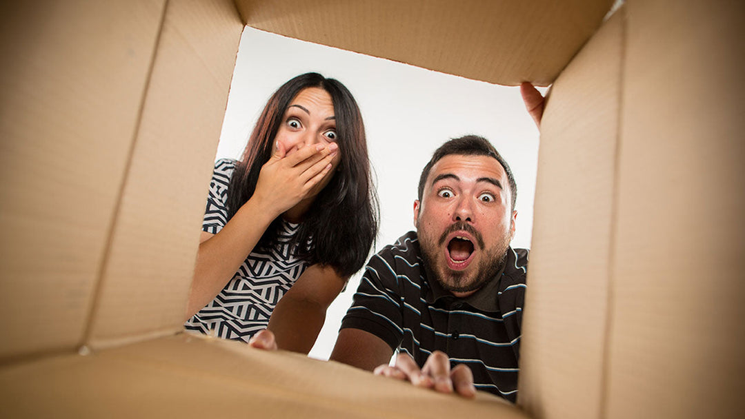Surprised and happy couple looking in a shipping box at their wedding favors.
