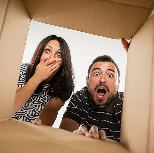 Surprised and happy couple looking in a shipping box at their wedding favors.