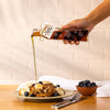 Pouring of maple syrup out of our autumn leaf bottle over French toast and fruit.