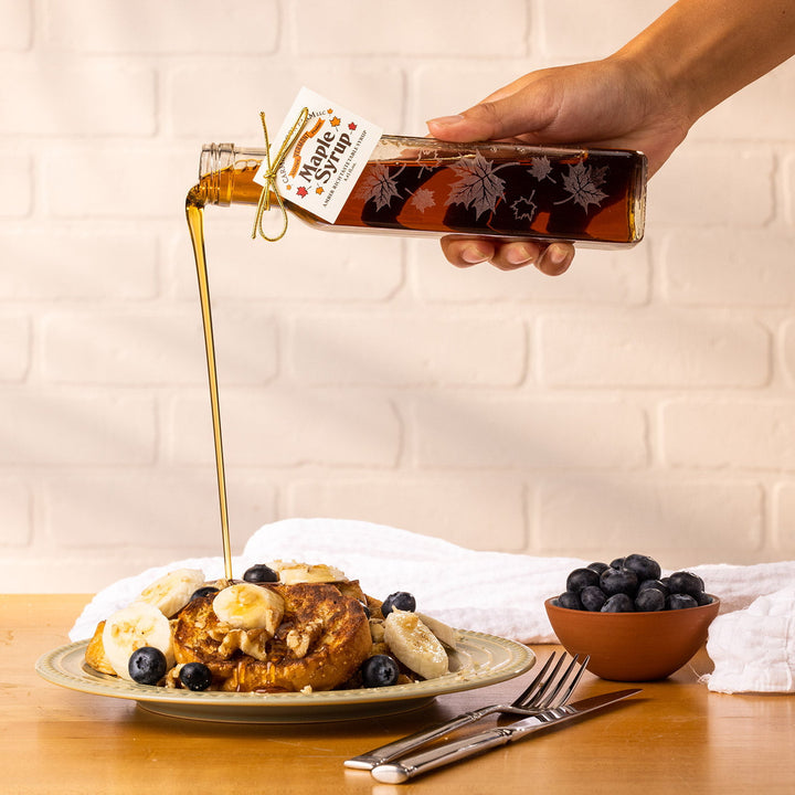 Pouring Vermont maple syrup from Autumn Leaf glass bottle onto waffles.