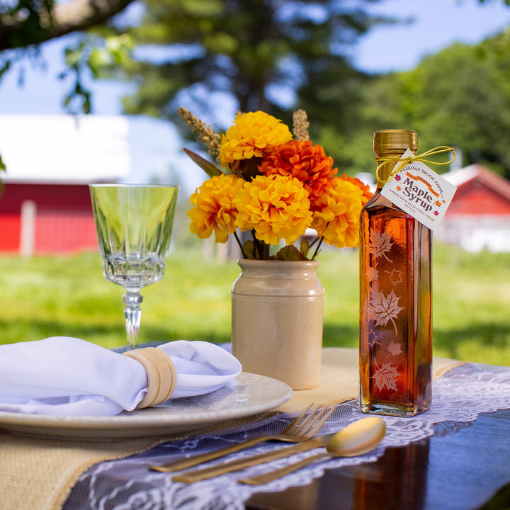 Autumn Leaf Vermont maple syrup bottle displayed on rustic outdoor table.
