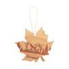 Maple leaf wooden ornament with a deer engraving jumping over a fence in the woods.