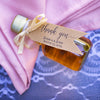 A hang tag and ribbon outfits the gallone wedding bottle in a dusty rose table setting.