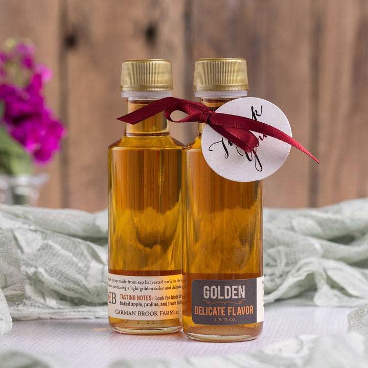 Golden delicate Vermont maple syrup wedding favor bottle styled with ribbon and tag.