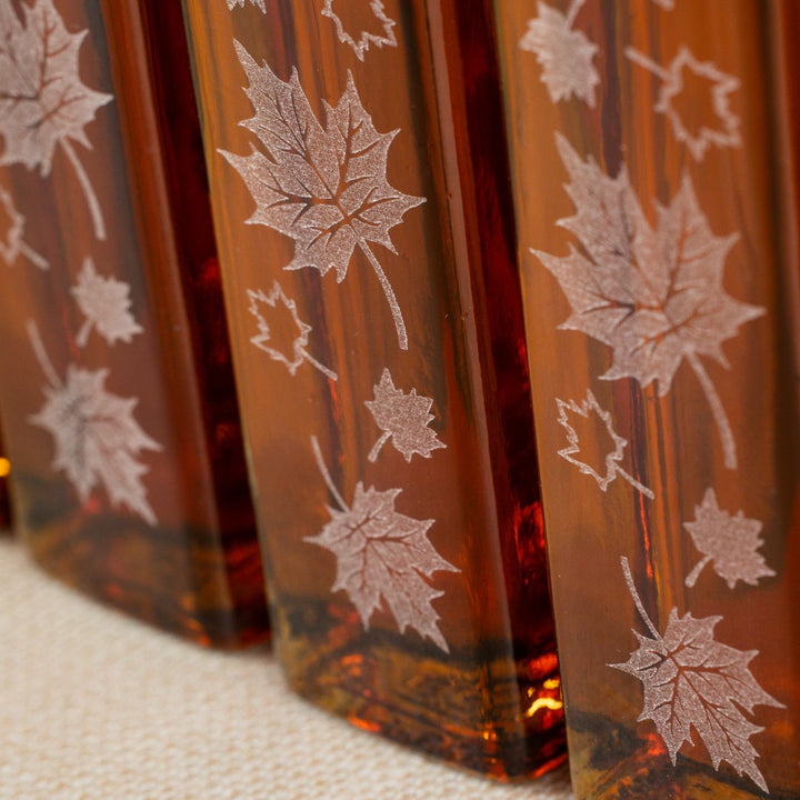 Detailed etching on autumn leaf glass bottle for maple syrup wedding favors.