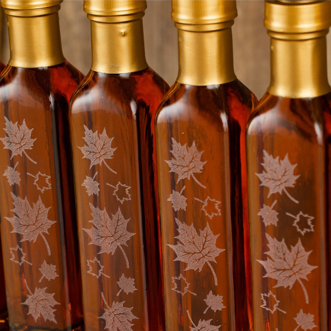 Close up of engraved maple leaf design on 8.45 oz glass maple syrup wedding favor bottle.